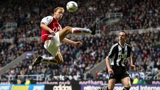 dennis bergkamp wearing arsenal kit jumping to catch a ball against newcastle united