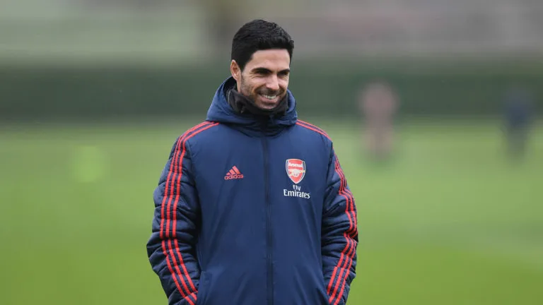 mikel arteta wearing a blue jacket and smilind suring training with arsenal