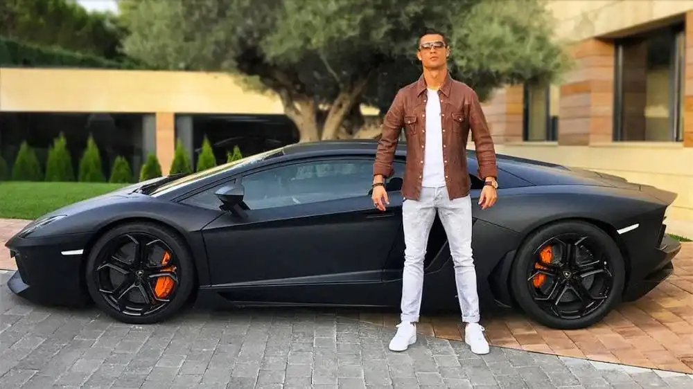 cristiano ronaldo sitting in front of a black bugatti