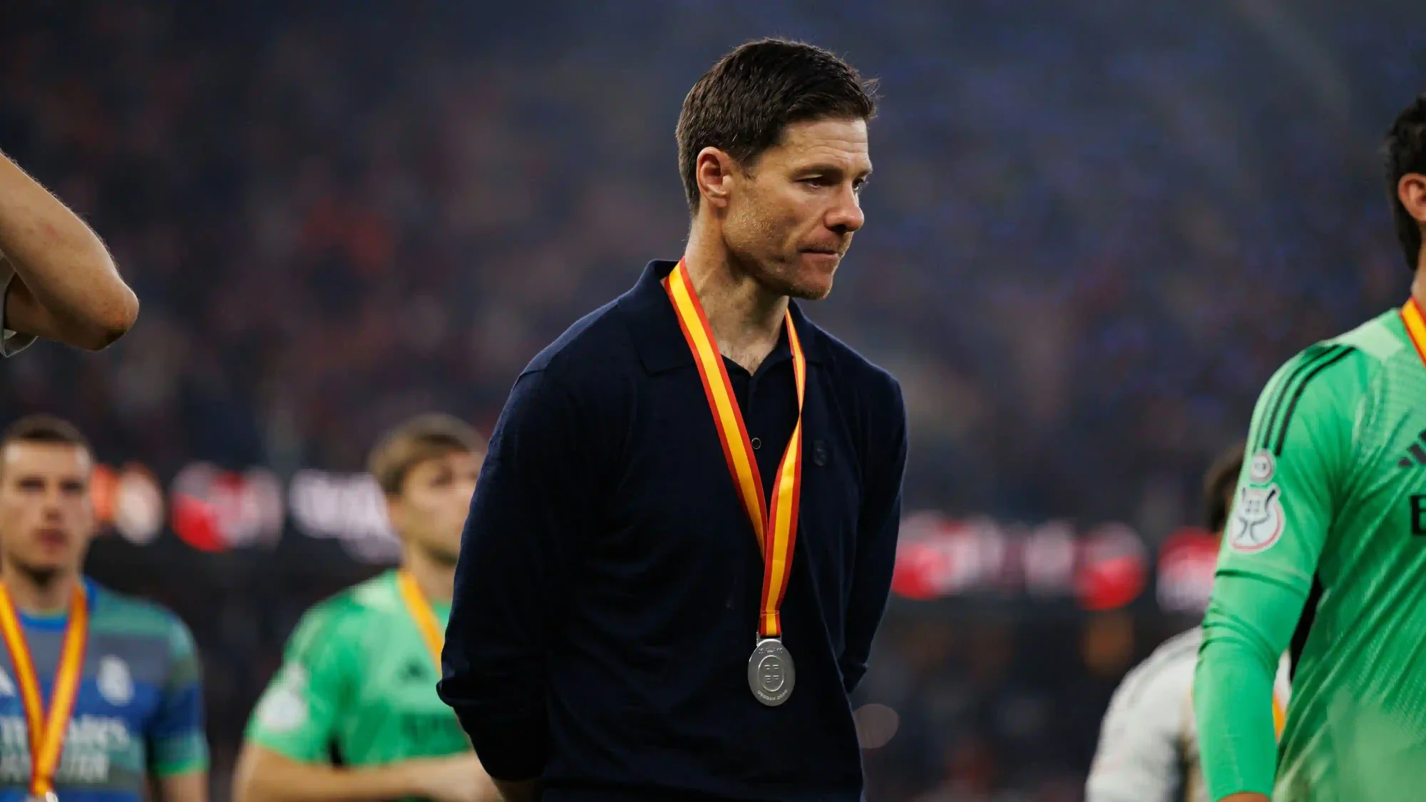Xabi Alonso stands with a medal around his neck during a post-match ceremony.