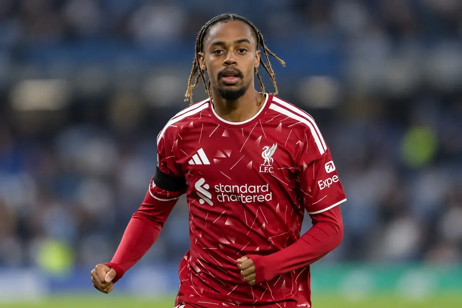 Bradley Barcola in a red Liverpool kit running against a blurred stadium background.