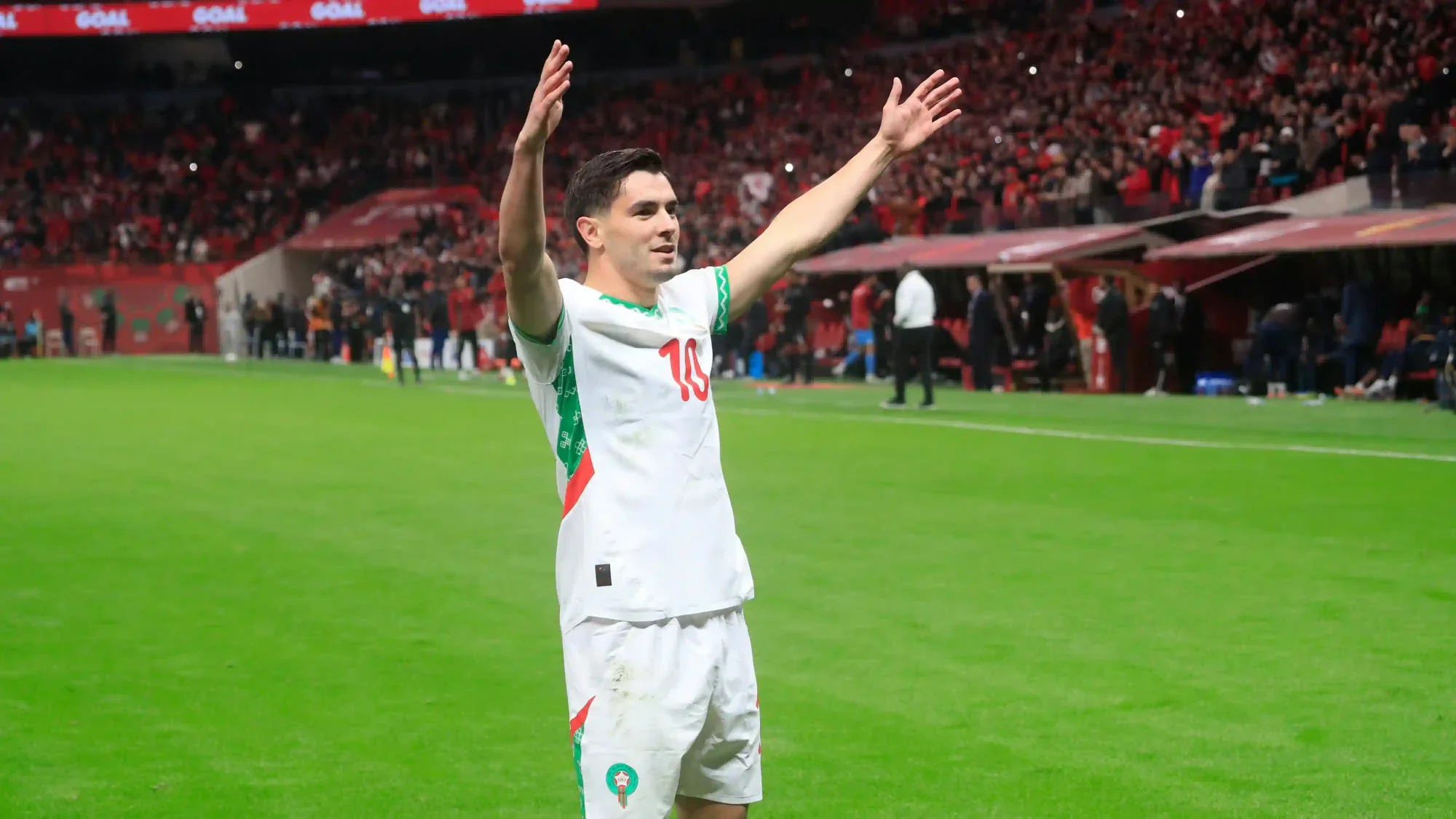 Brahim Diaz raises his arms to the crowd after a match at a packed stadium.
