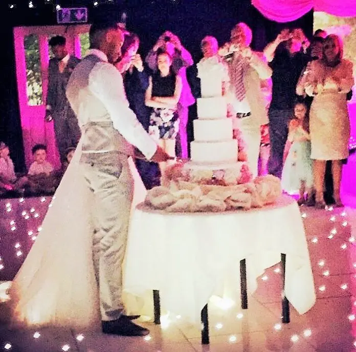 callum wilson and stacey wilson cutting their wedding cake while people are filming them