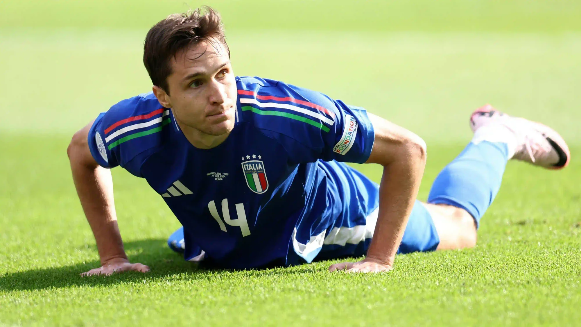 Federico Chiesa lies on the pitch in Italy’s number 14 shirt during a match.