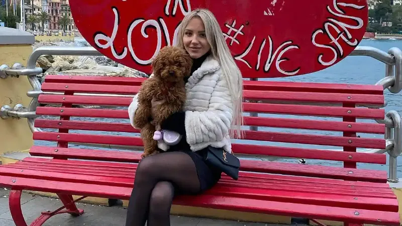 claudia kowalczyk wearing black skirt and white jacket holding a dog