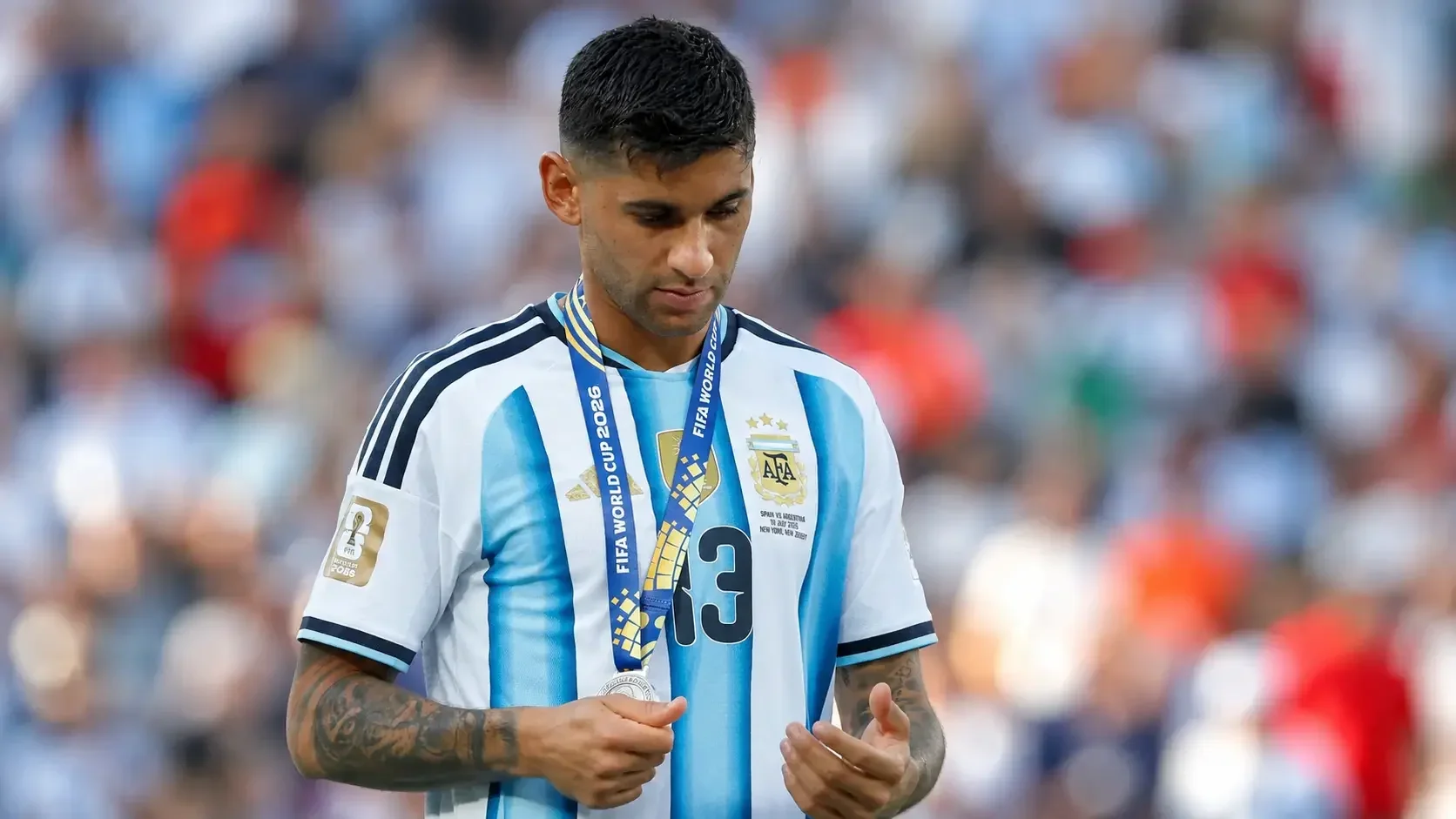 Cristian Romero wearing an Argentina shirt and holding his World Cup medal