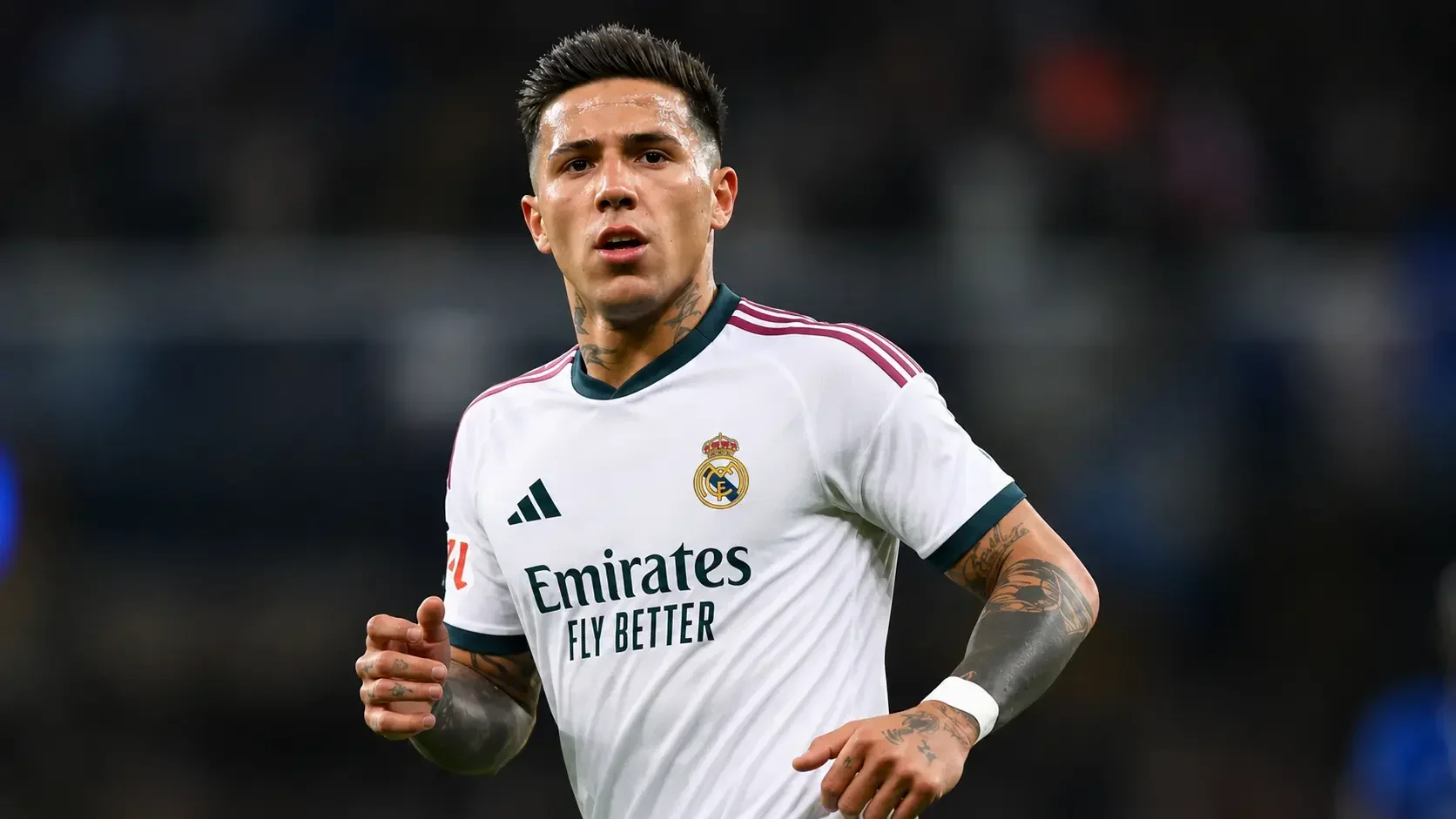 Enzo Fernandez wearing a Real Madrid home kit during a match, running with focus and determination in a stadium under bright floodlights.