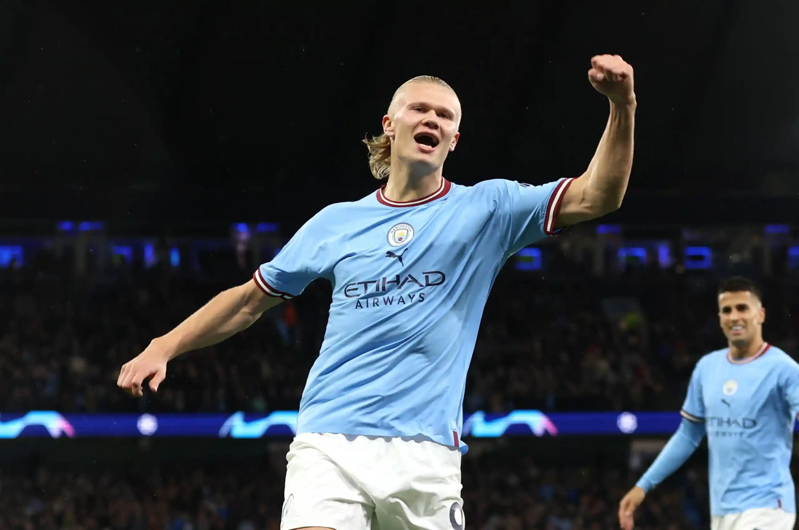 erling haaland jumping in the air to celebrate after scoring a goal for man city