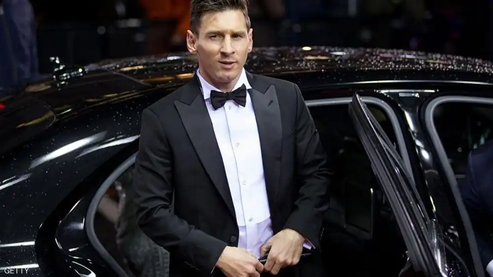 lionel messi wearing black tuxedo standing in front of a black lux car