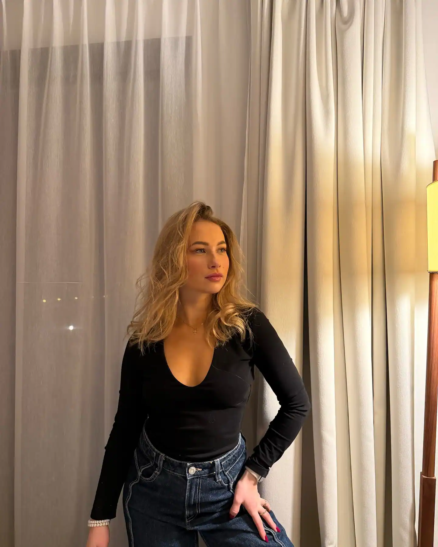 floraine allain posing in front of beige curtain in her living room
