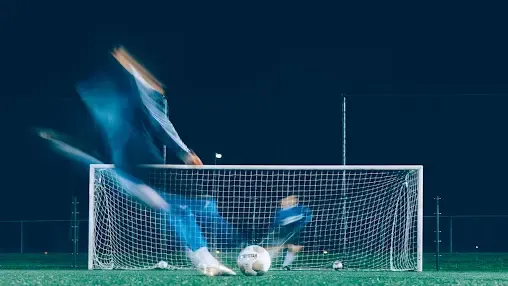 blurred image of a footballer shootiong at the golakeeper