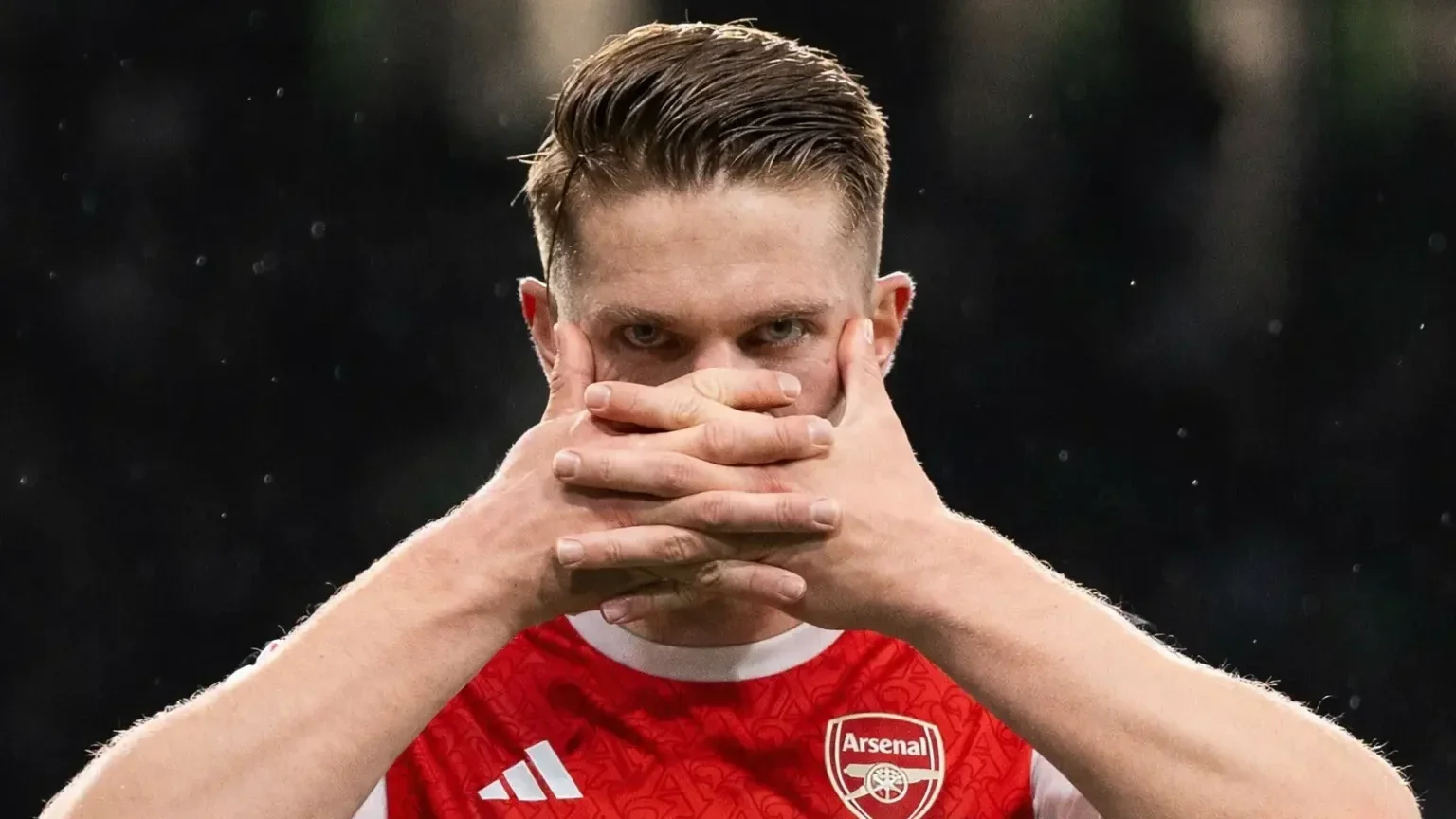 Viktor Gyökeres in an Arsenal shirt covering his mouth with his hands during a match celebration.