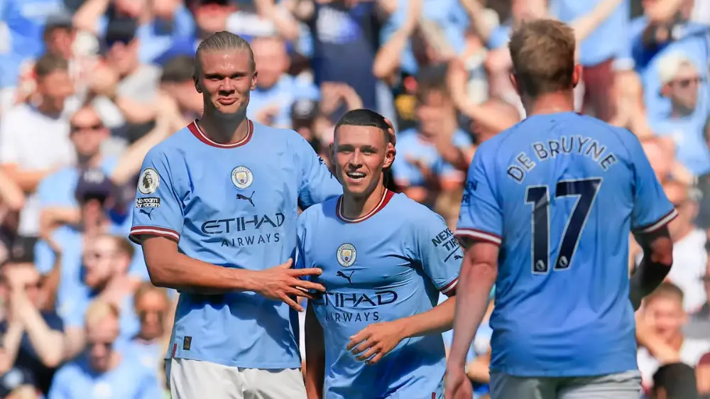 erling haaland hugging phil foden and kevind de bruyne walking towards them after scoring a goal