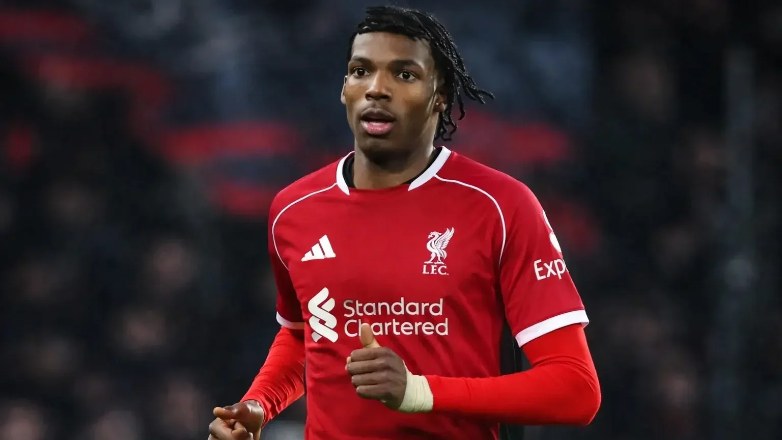 Jacquet running during a match while wearing a Liverpool red home kit, with a blurred stadium crowd in the background.