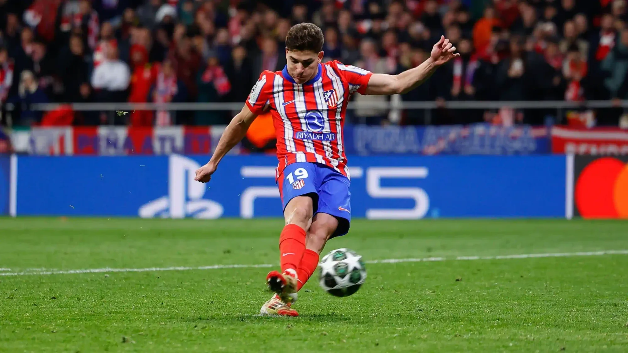 julián álvarez shoots for atlético madrid in a champions league match, striking the ball with his left foot