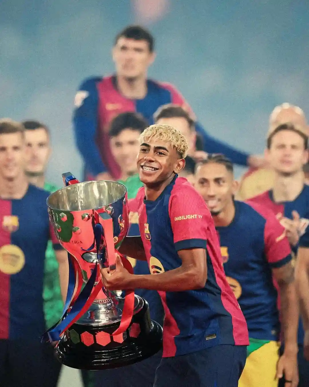 lamine yamal lifting a title with barcelona and his teammates cheering