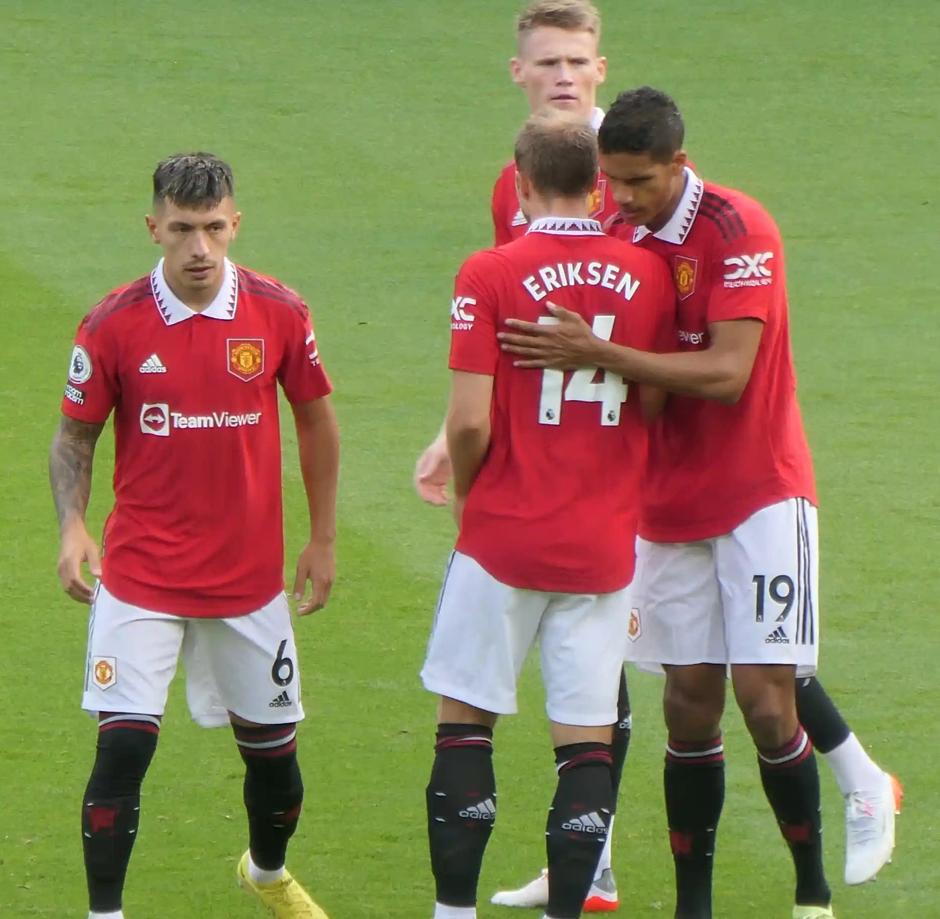 lisandro martinez standing next to christian eriksen and raphael varane who are hugging