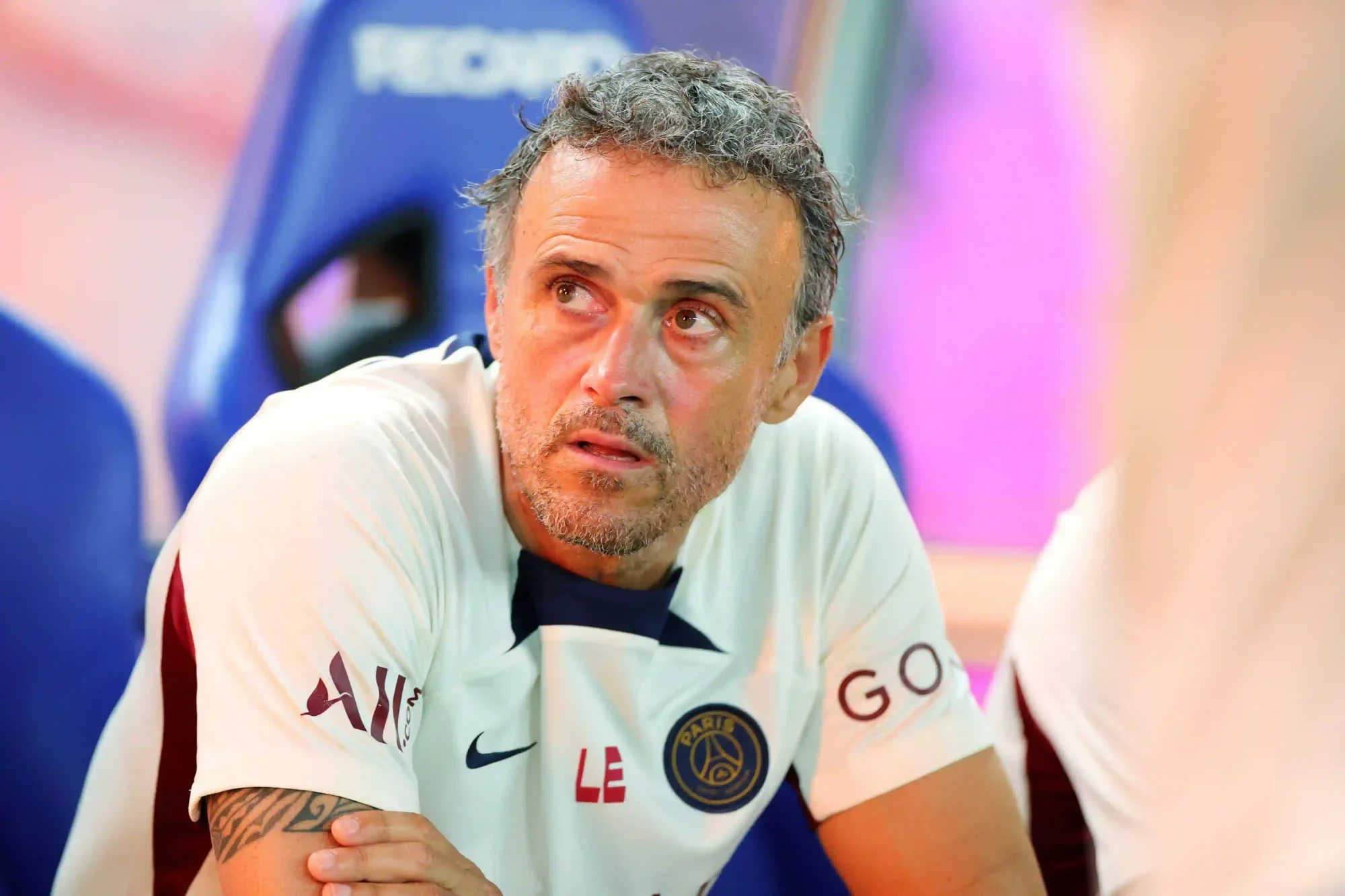 luis enrique sits on the bench wearing a psg training top during a match