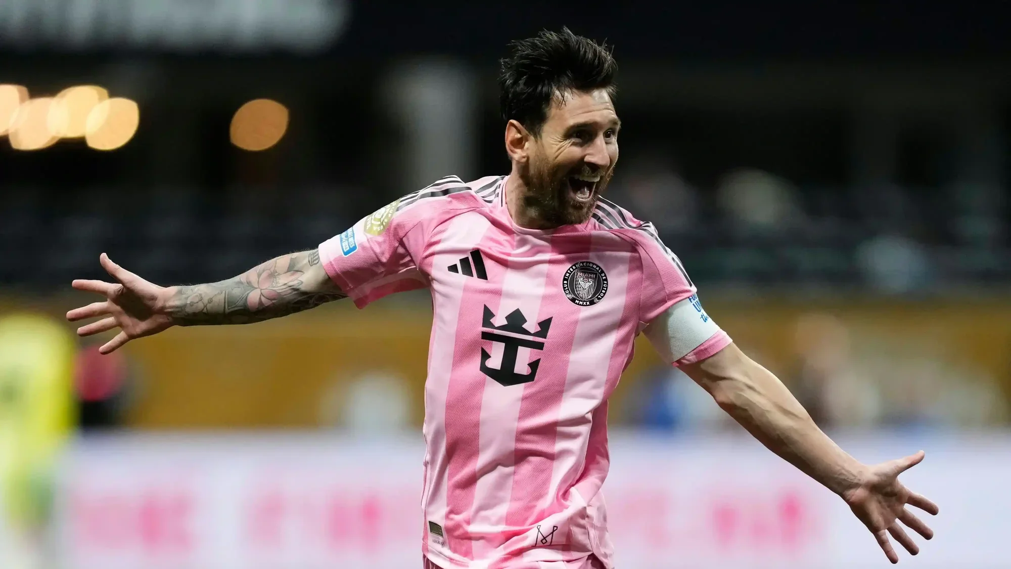 Lionel Messi celebrates with arms outstretched wearing Inter Miami’s pink kit during a match.
