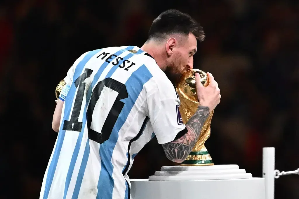 Lionel Messi kisses the FIFA World Cup trophy while wearing Argentina’s number 10 shirt.