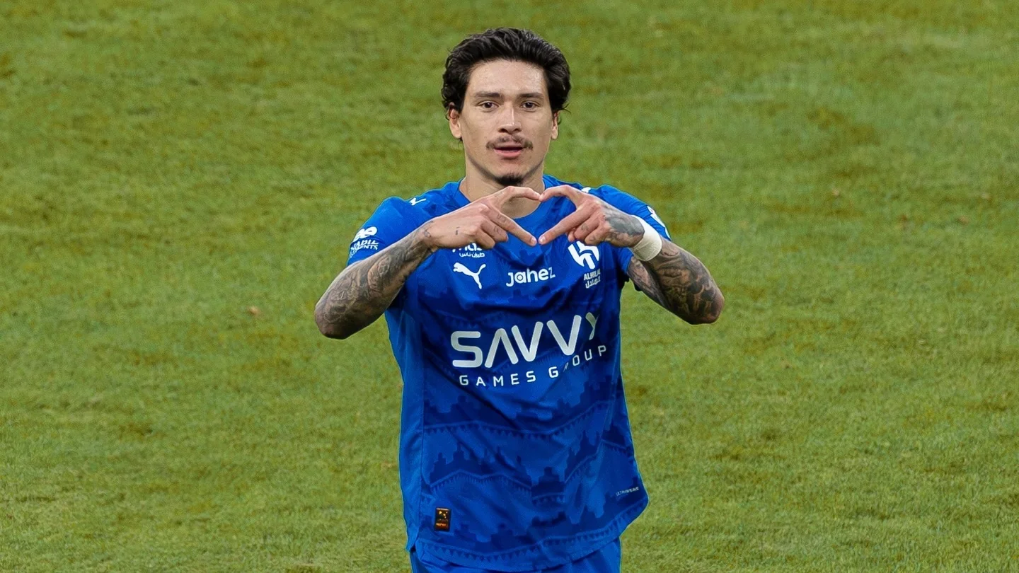 Darwin Nunez in a blue kit of Al hilal celebrating on the pitch, forming a heart gesture with his hands after scoring.