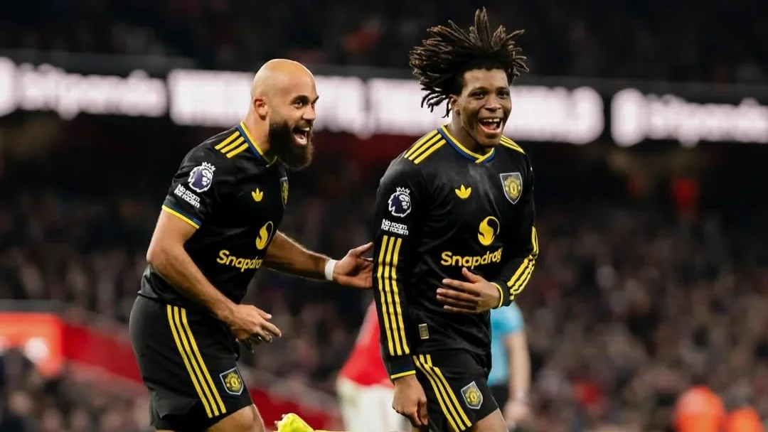 Patrick Dorgu and Bryan Mbeumo celebrating together in Manchester United’s black away kit during a match.