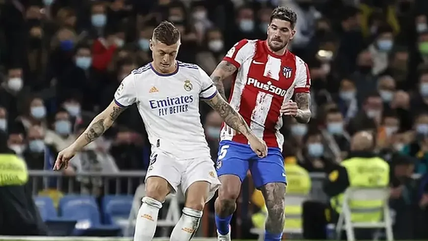 real madrid toni kroos and atletico madrid rodrigo de paul challenging for a ball