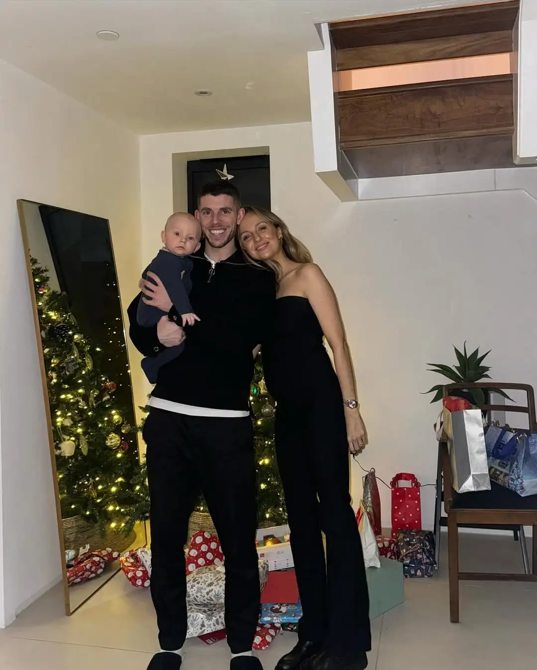 ryan christie and georgie christie with their son in front of their christams tree in their home