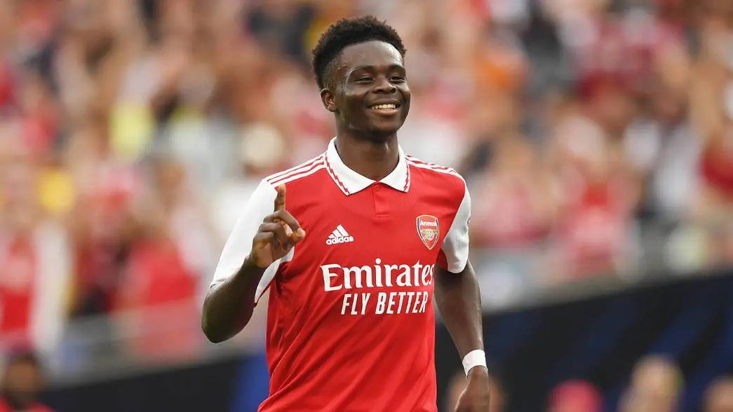 bukayo saka with arsenal 2022/23 kit smiling after scoring a goal