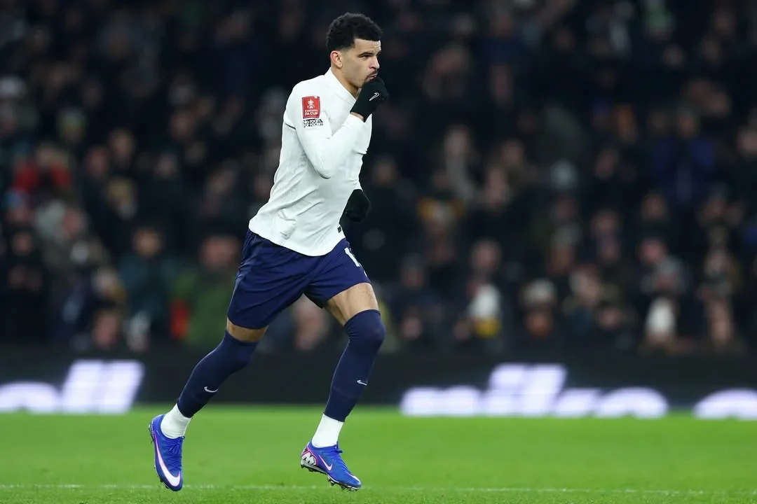 Dominic Solanke runs on the pitch during a match, wearing a white shirt and navy shorts.