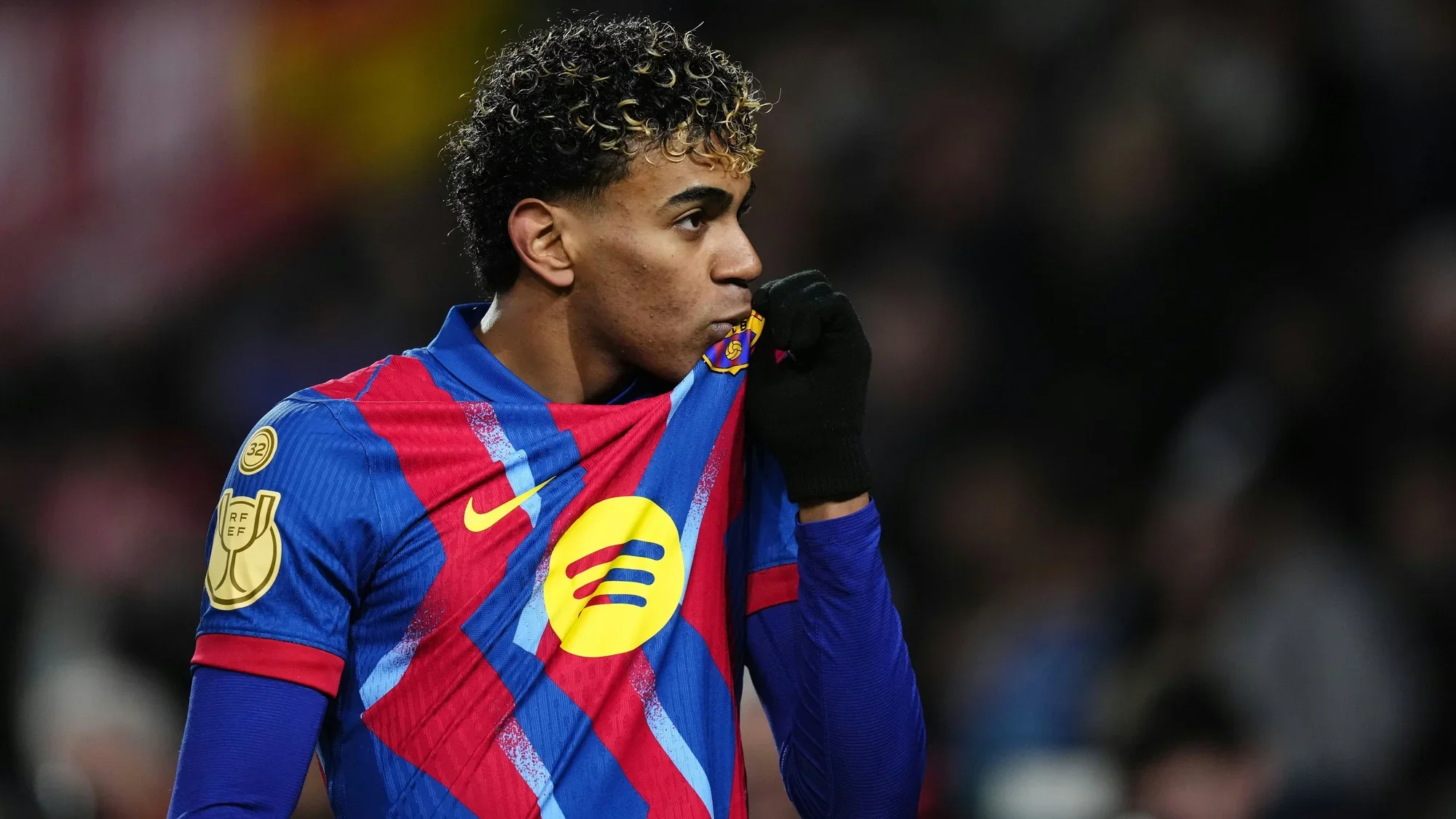 lamine yamal kissing the badge of his shirt wearing barca colors